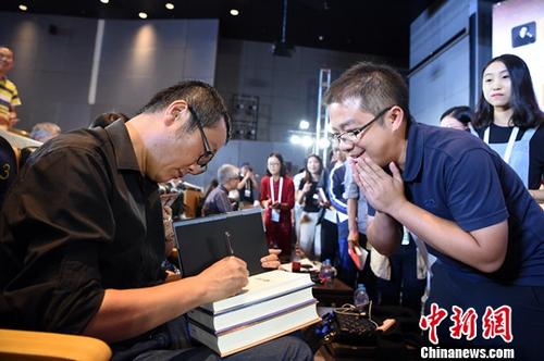 资料图:2018年9月18日,世界公众科学素质促进大会的“科幻在促进公众科学素质中的先锋价值”专题讨论在北京中国科技馆举行。图为中国著名科幻作家刘慈欣(左)为“粉丝”签名。<a target='_blank' href='http://www.chinanews.com/' _fcksavedurl='http://www.chinanews.com/' _fcksavedurl='http://www.chinanews.com/'>中新社记者 侯宇 摄 点击进入下一页
